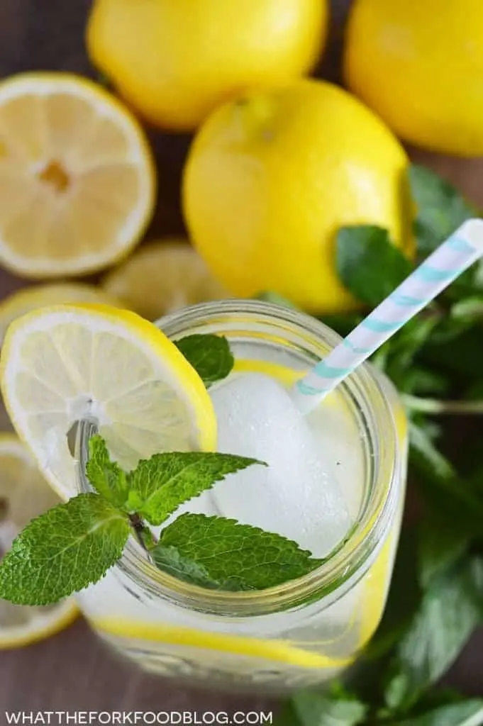 Delicious and simple vodka lemonade in a glass with a straw topped with lemon and mint