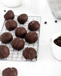 homemade chocolate truffles dipped in chocolate and sprinkled with sea salt on a small wire rack
