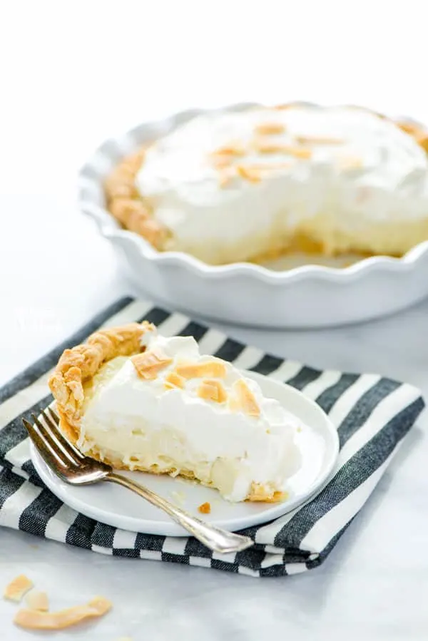 Coconut Cream Pie is a true dessert comfort food! Flaky pie crust filled with creamy coconut custard, layered with sweet fresh whipped cream and topped with toasted coconut. It’s a DREAM! Make it with a gluten free pie crust or a regular pie crust, your choice! This easy pie recipe is great for any holiday or get together. Easy dessert recipe from @whattheforkblog - visit whattheforkfoodblog.com for more! #glutenfree #pie #coconut #dessert #easydessert #recipe #dessertrecipes #coconutrecipes