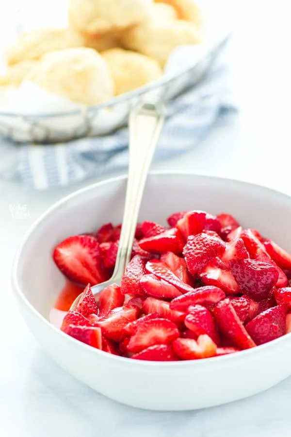 Sliced strawberries in a white bowl ready to be made into gluten free strawberry shortcake