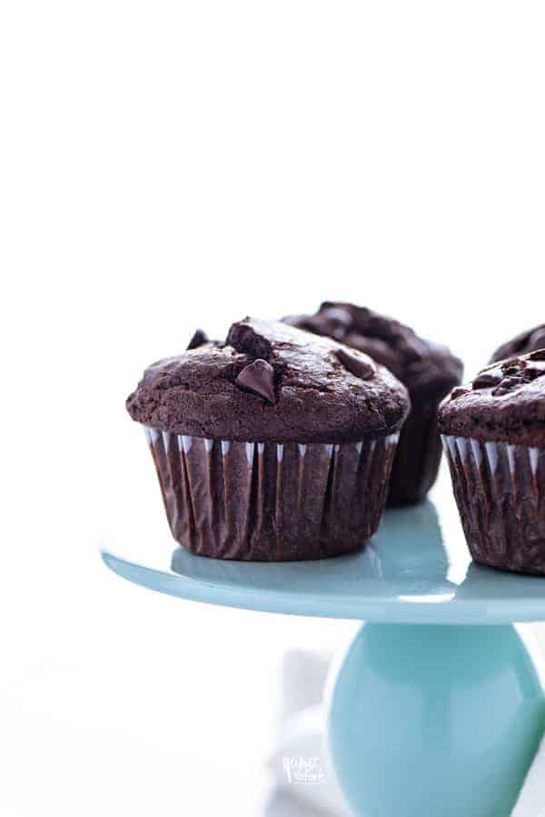 Gluten Free Bakery Style Double Chocolate Chip Muffins displayed on a blue cake stand