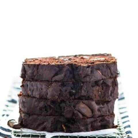 Gluten Free Double Chocolate Zucchini Bread sliced and stacked on a striped towel and rack