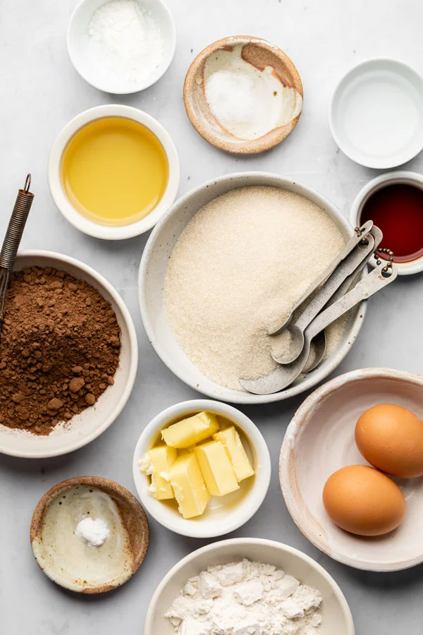 Important ingredients for fudgy brownies including eggs, butter, cocoa powder, sugar, milk, gf flour and sugar