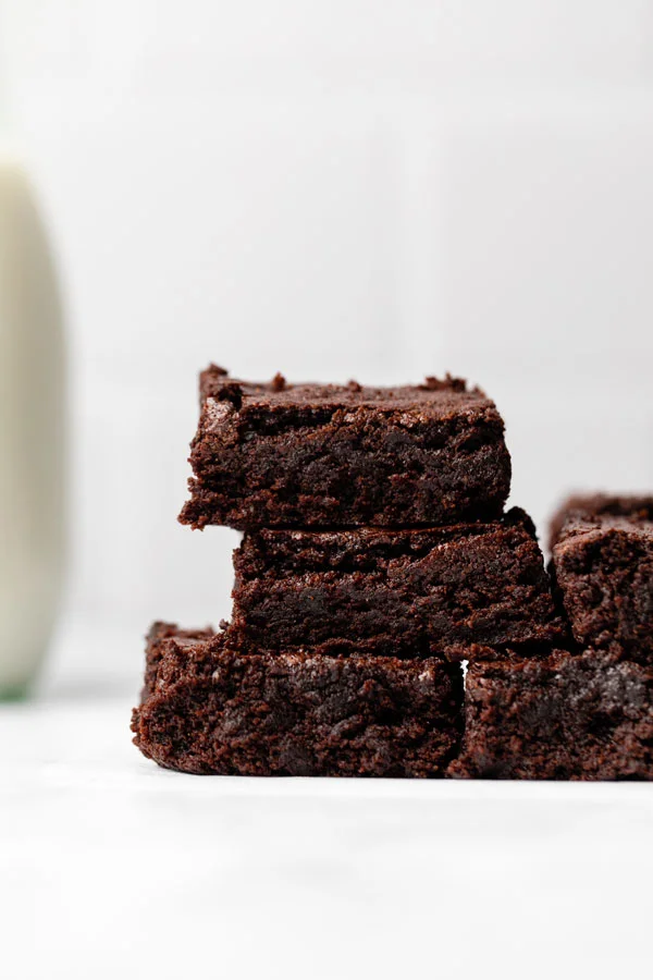 sliced gluten free brownies on a parchment paper lined wood cutting board