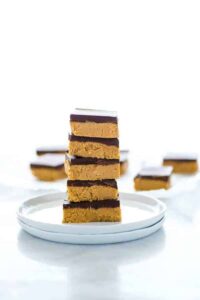 A stack of gluten free chocolate peanut butter bars on a white plate.