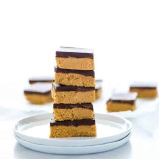 A stack of gluten free chocolate peanut butter bars on a white plate.