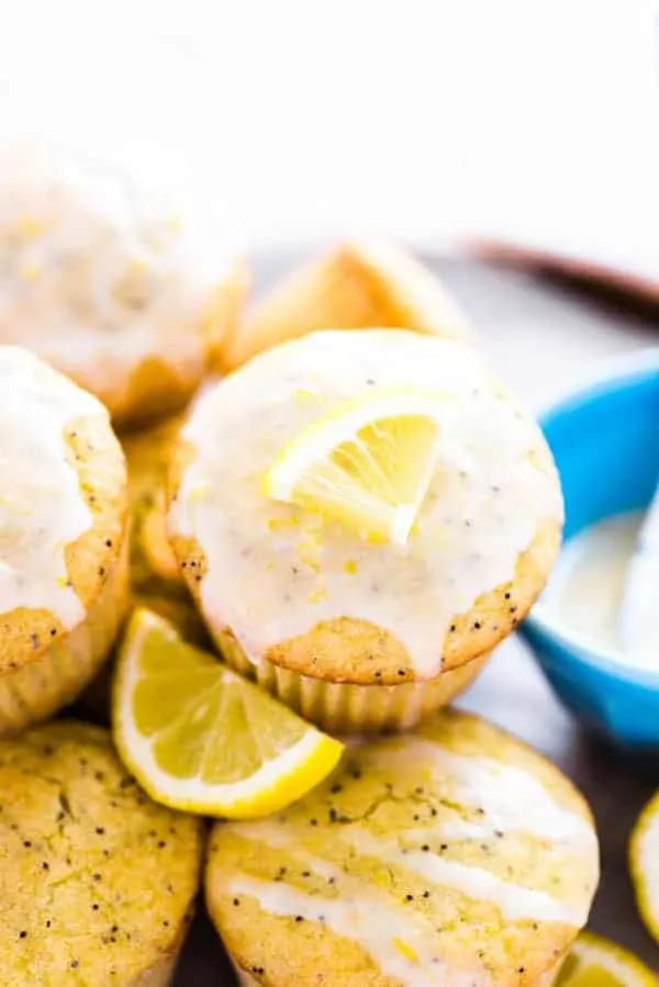 These gluten free lemon poppy seed muffins are a great breakfast recipe to make in the spring. They’re super easy to make and can easily be made dairy free. They’re packed with lemon punch with lemon juice, lemon zest, and lemon extract. And don’t skip the lemon glaze! From @whattheforkblog | whattheforkfoodblog.com | gluten free muffin recipes | easy gluten free breakfast recipes | homemade lemon poppy seed muffins | #glutenfree #breakfast #muffins #lemon #lemonpoppyseed close up of gluten free lemon poppy seed muffin with a slice of lemon for garnish