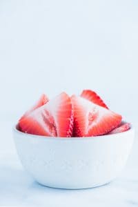 sliced strawberries in a white bowl