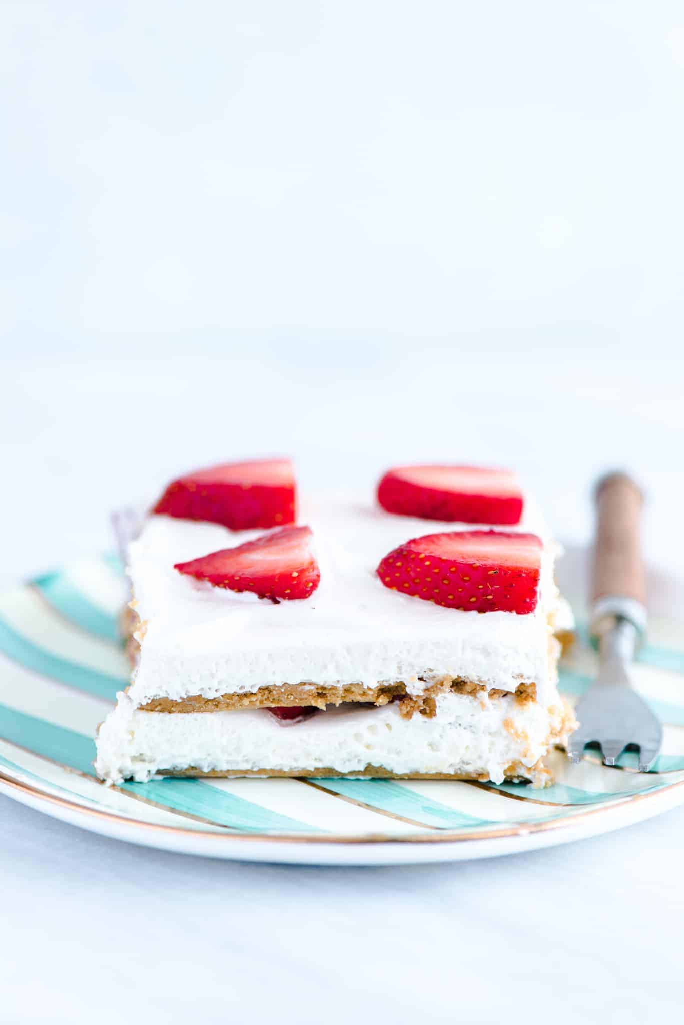 A slice of gluten free strawberry icebox cake on a green and white striped plate