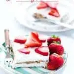 gluten free strawberry icebox cake slice on a plate with a small fork and strawberries