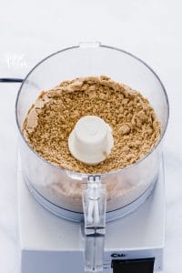 Crushed graham cracker crumbs in a food processor to show how to make a graham cracker crust