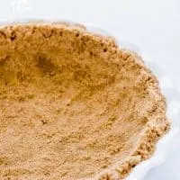 A finished gluten free graham cracker crust in a white pie dish