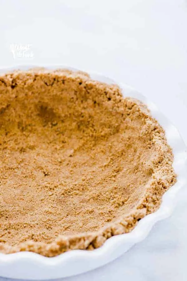 A finished gluten free graham cracker crust in a white pie dish