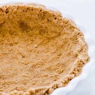 A finished gluten free graham cracker crust in a white pie dish