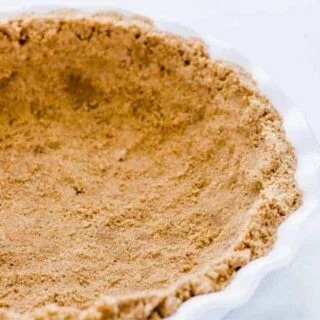 A finished gluten free graham cracker crust in a white pie dish