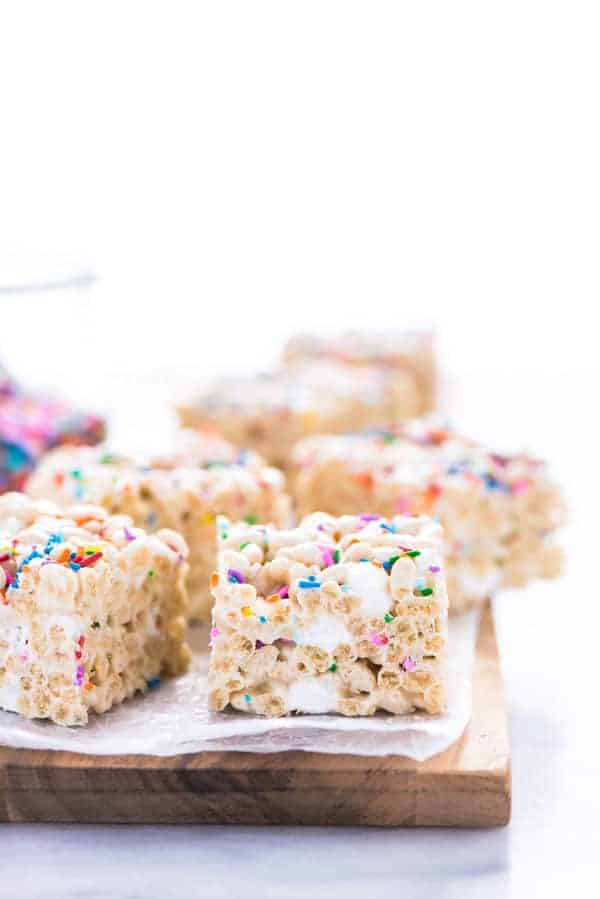 Gluten Free Rice Krispies Treats arranged on a brown wood cutting board