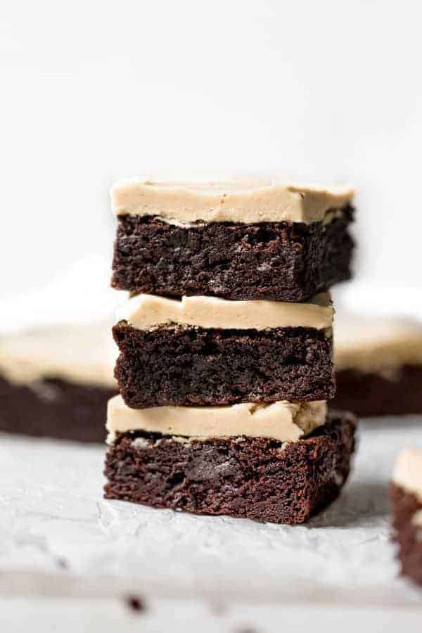 Stack of three gluten free brownies with peanut butter frosting.