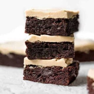 Stack of three gluten free brownies with peanut butter frosting.