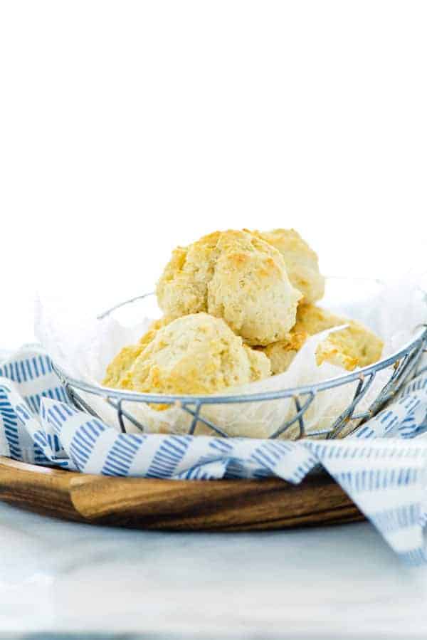 Des Drop Biscuits sans gluten dans une corbeille à pain grillagée avec une serviette bleue