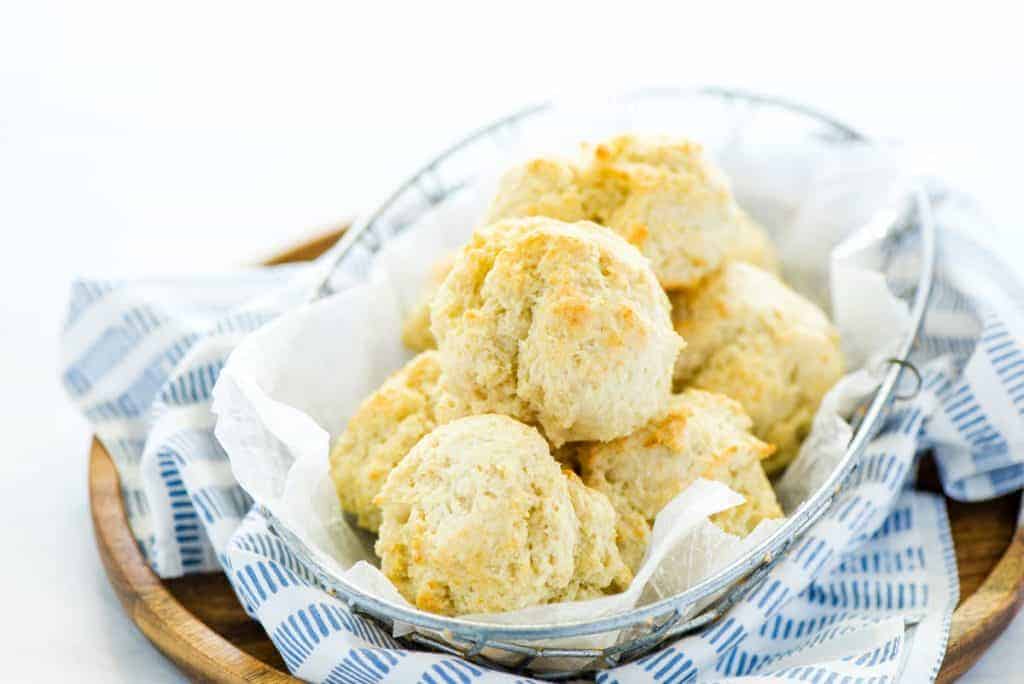 gluten free drop biscuits in a wire bread basket with parchment paper and a blue striped towel