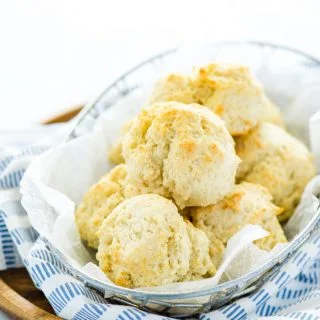 gluten free drop biscuits in a wire bread basket with parchment paper and a blue striped towel