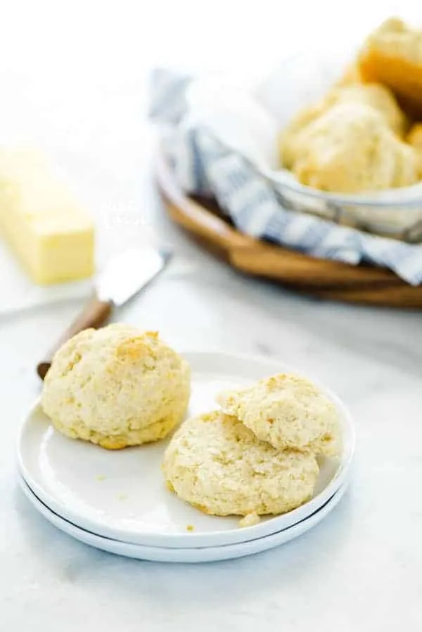 gluten free drop biscuits on a white plate with one whole and one sliced open