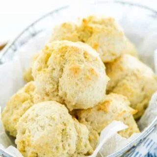 gluten free drop biscuits in a wire bread basket with parchment paper and a blue striped towel