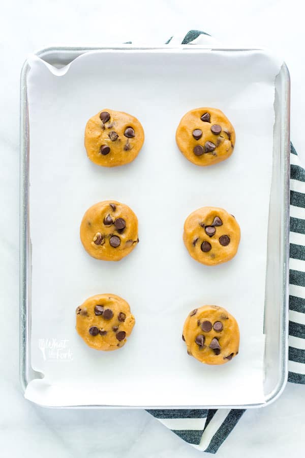 Gluten Free Chocolate Chip Cookie Dough ready to be baked on a silver baking pan and parchment paper.