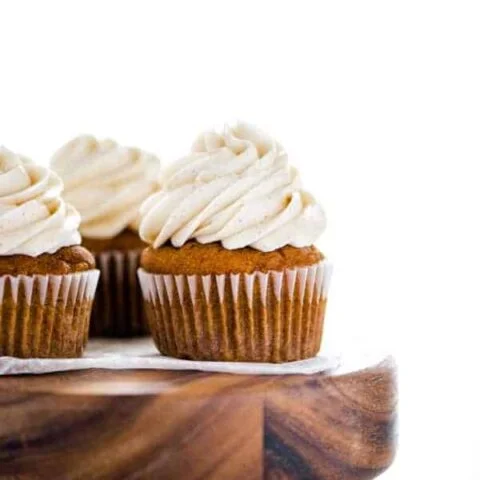 Gluten Free Pumpkin Cupcakes with Cinnamon Cream Cheese Frosting on a round wood cake stand