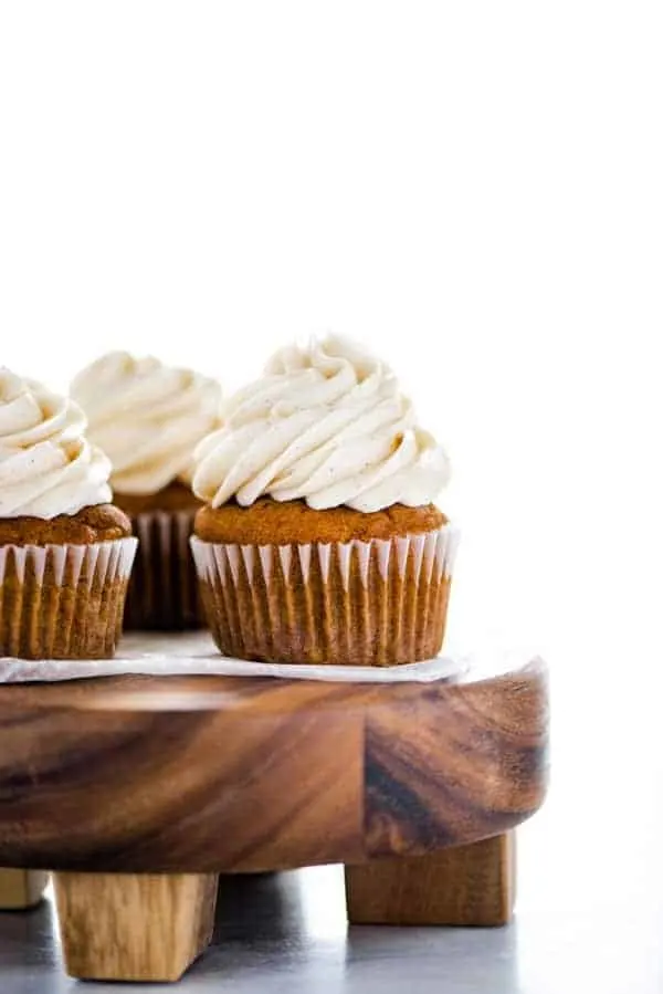 Gluten Free Pumpkin Cupcakes with Cinnamon Cream Cheese Frosting on a round wood cake stand