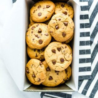 Gluten Free Peanut Butter Chocolate Chip Cookies in a vintage loaf pan with white parchment paper and a striped towel.