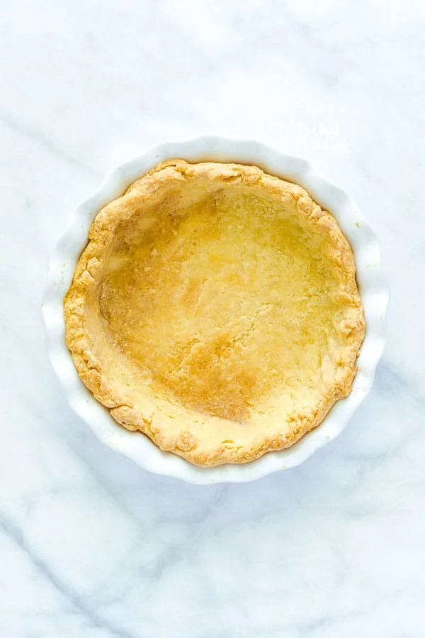 A blind baked pie crust in a white pie plate
