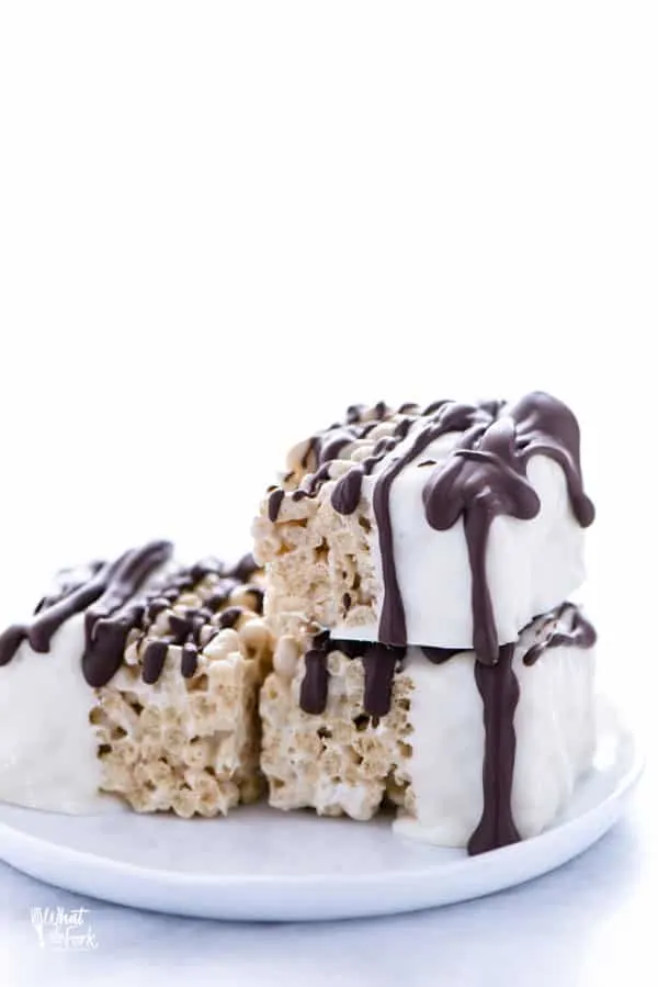 Three Chocolate Dipped Rice Krispie Treats on a white plate