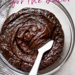 Brownie batter in a glass bowl with a white spatula with text for kitchen tools for the baker
