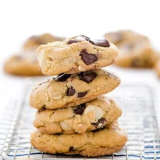 A stack of gluten free Chocolate Macadamia Nut Cookies on a small wire rack.