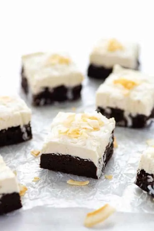 Slices of Gluten Free Brownies with Coconut frosting on wax paper ready to serve.