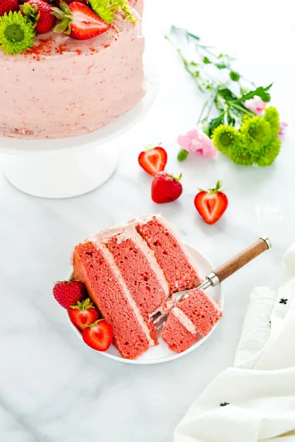 Made from scratch Gluten Free Strawberry Cake made with fresh strawberries, no extracts or artificial flavors! This cake is moist and VERY full of fresh strawberry flavor. Finish it off with homemade strawberry cream cheese frosting and garnish with fresh strawberries, a dusting of freeze-dried strawberry powder, and edible flowers for a gorgeous presentation. This makes a 3-layer 8-inch cake or halve the recipe for 2 6-inch layers. #strawberrycake #strawberryrecipes #cake #glutenfree #dessert