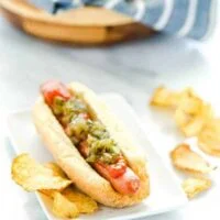 Gluten Free Hot Dog Buns filled with a hot dog and topped with ketchup and relish and potato chips on the side.