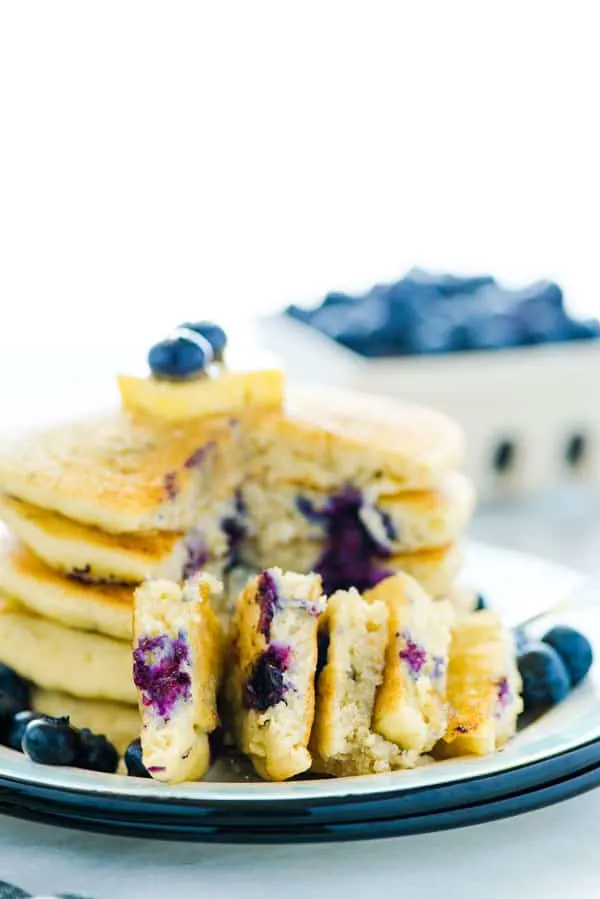 Easy homemade fluffy Gluten Free Blueberry Pancakes are full of fresh blueberries bursting with flavor. Great for breakfast, brunch, or dinner. Plus they freeze well so make a double batch to save some for later! This recipe makes the best blueberry pancakes! Gluten Free breakfast recipe from @whattheforkblog - visit whattheforkfoodblog.com for easy gluten free recipes! #glutenfree #pancakes #breakfast #easyrecipe #blueberry #blueberrypancakes