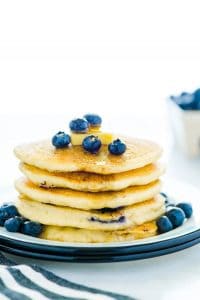 Gluten Free Blueberry Pancakes stacked on a plate and garnished with fresh blueberries