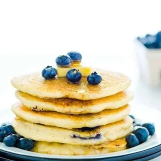 Gluten Free Blueberry Pancakes stacked on a plate and garnished with fresh blueberries