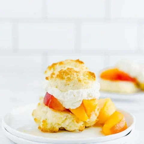 Gluten Free Peach Shortcake on a white plate garnished with fresh peaches