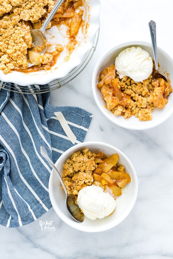 Two bowls of gluten free apple crisp with a scoop of vanilla ice cream gluten free is the feature recipe for a roundup of gluten free apple recipes
