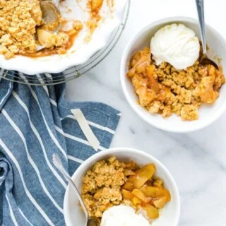 Two bowls of gluten free apple crisp with a scoop of vanilla ice cream