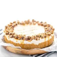 Gluten Free Chocolix No Bake Cheesecake recipe on a round wood board lined with wax paper.