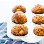Gluten Free Apple Muffins in a white muffin pan on a blue and white striped kitchen towel.