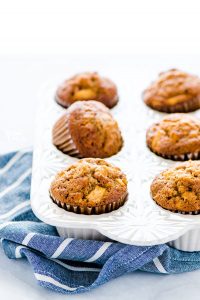 Gluten Free Apple Muffins in a white muffin pan on a blue and white striped kitchen towel.