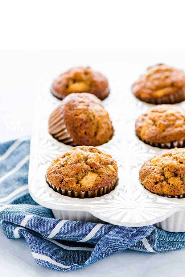 Gluten Free Apple Muffins in a white muffin pan on a blue and white striped kitchen towel.