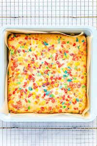 Baked Gluten Free Fruity Pebbles Cake with Cereal Milk in a square baking pan on a wire rack