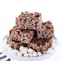 Gluten Free Chocolate Rice Krispie Treats stacked on a white cake stand garnished with mini marshmallows